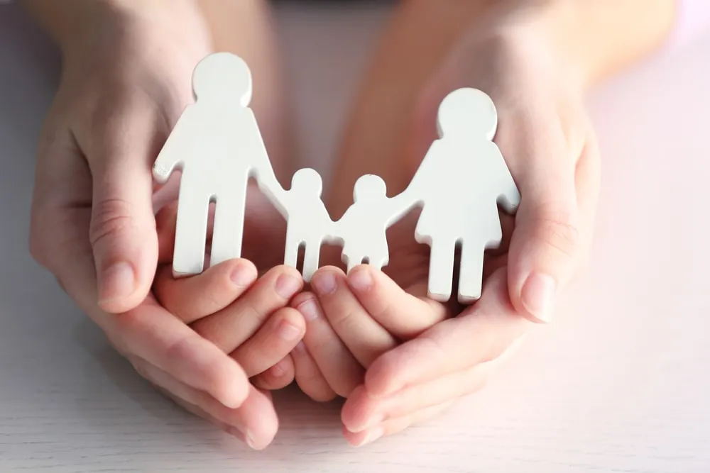 Hands holding a paper family cut-out